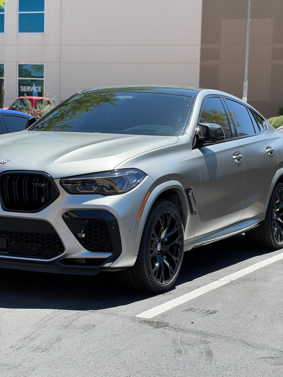 Matte Silver BMW SUV parked in a parking lot with a building in the background