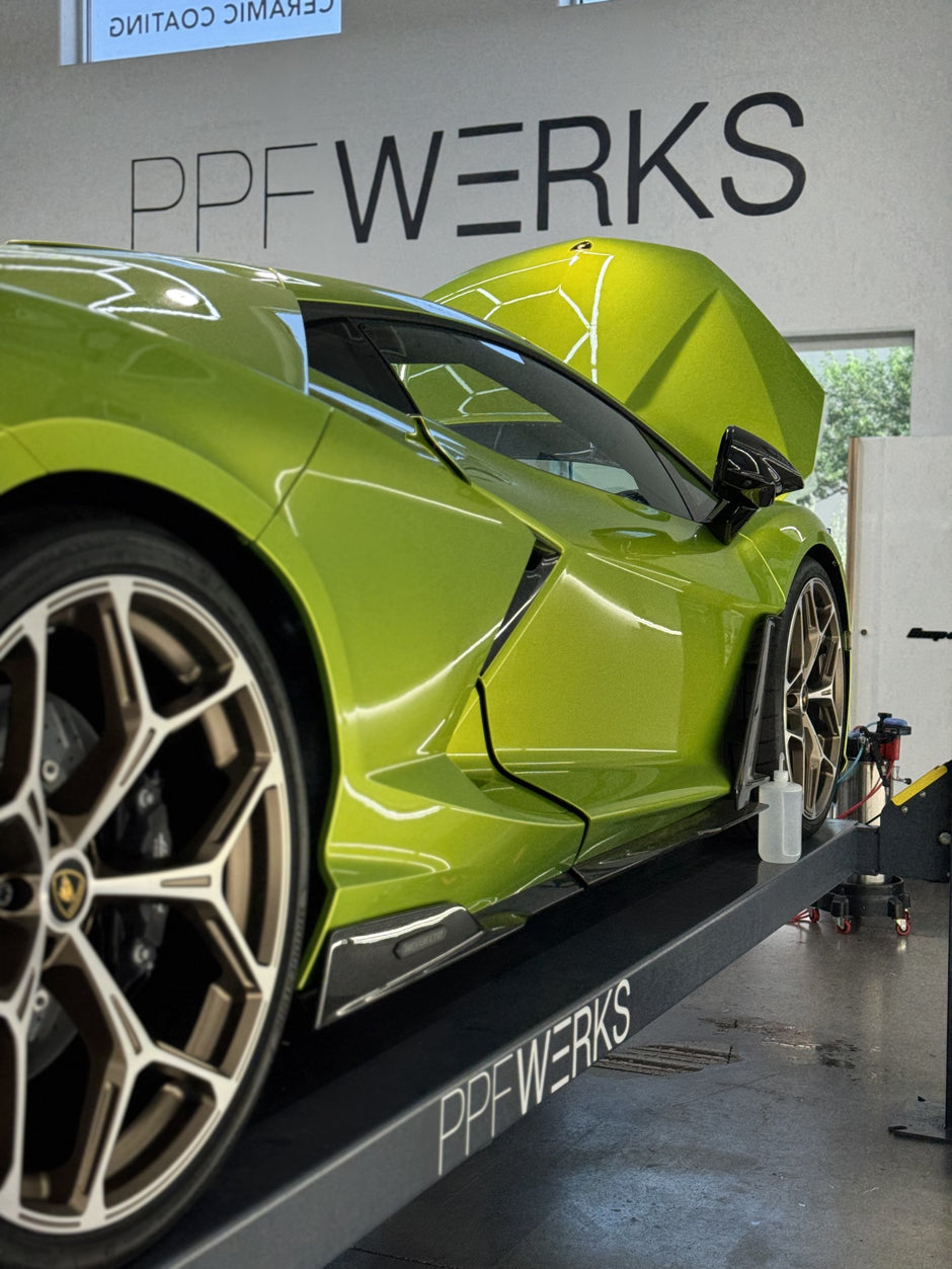 Green Lamborghini on a lift with 'PPF Werks' branding in a garage.
