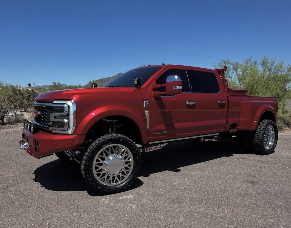 Red pickup truck on a paved road with a desert landscape in the background