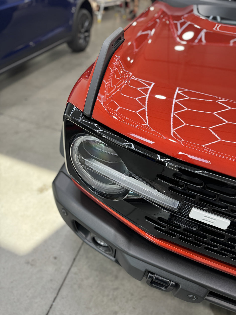 Close-up of a red bronco front grille with a spider web design.