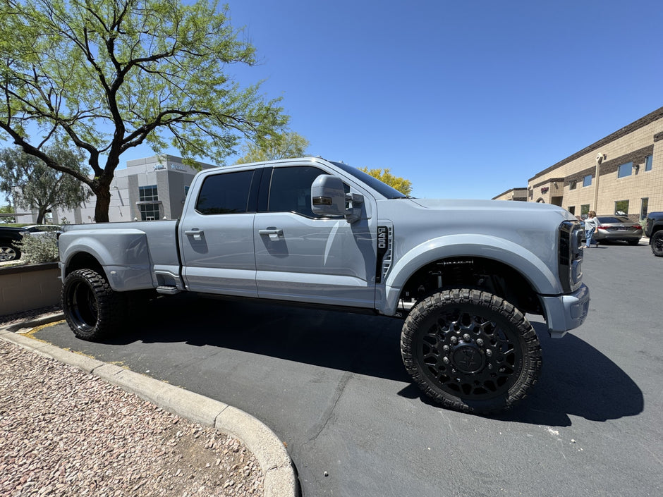 Blue F450 pickup truck with large wheels parked on a street