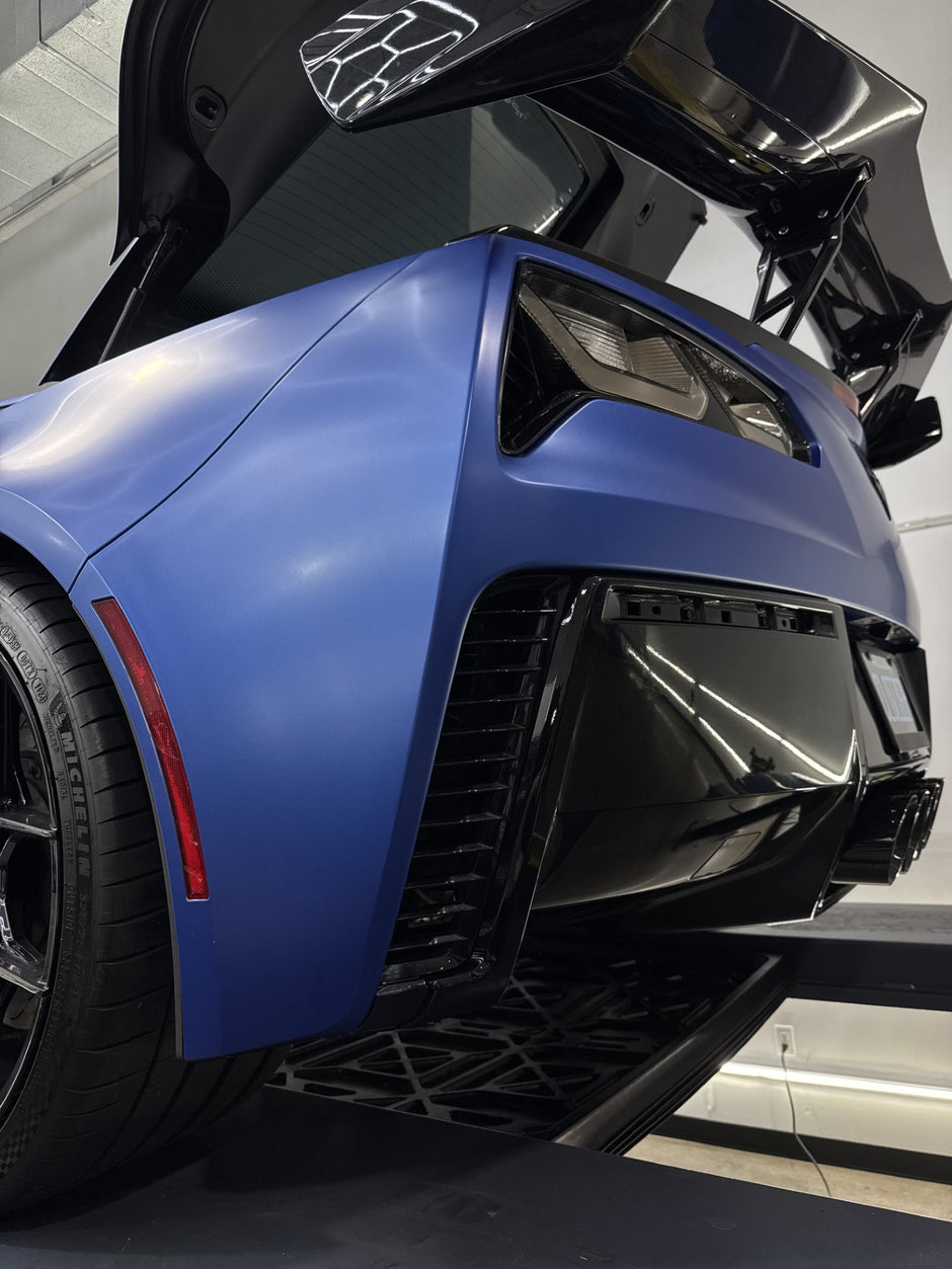 Close-up of a blue corvette rear bumper in a showroom setting