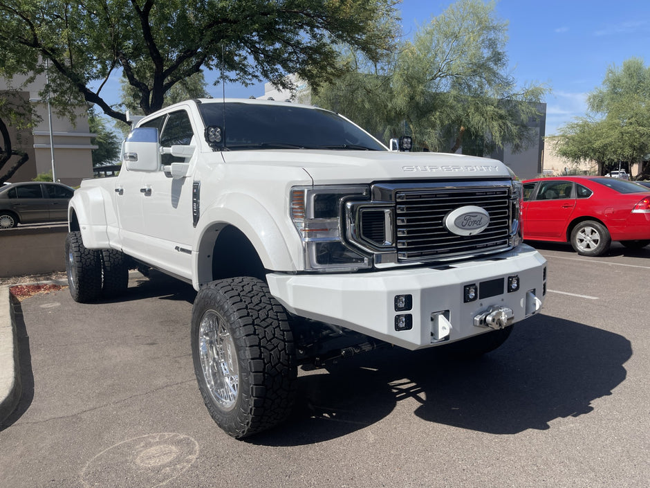 White Ford truck in a parking lot with trees and other vehicles in the background